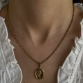 Person wearing a gold necklace with a pendant 